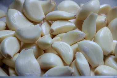 Bir yığın sarımsak karanfili, yemek pişirmek için doğal renklerini ve dokularını gösteren yakın bir görüntüde gösterilir..