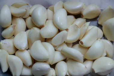 Pek çok soyulmuş sarımsak karanfilinin yakın plan çekimi, pişirme hazırlığı ve yemek ve yiyecekle ilgili içerik için lezzet katmaya hazır..