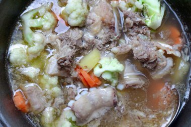 Et, karnabahar, havuç ve patates ile kaynayan bir çorbanın tepesinde, aşçılık projeleri için doyurucu ve rahatlatıcı bir yemek oluşturur..