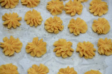 Çiçek şekilli birkaç kurabiye, pişirme ve ev yapımı tatlı içeriği için mükemmel desenli bir yüzeye sahip bir pişirme tepsisi üzerinde düzenlenir..