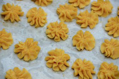 Sarı hamurlu kurabiyeler, yıldız şekli ve çiçekle pişirmeden önce pişirme tablasında dizayn edilir. Pişirme kavramları için harika bir tasarım..