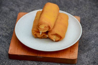 Peynirli dolgulu kızarmış börekler ahşap bir tabağın üzerine dizilir. Yemek fotoğrafçılığı ya da yemek tarifi çizimi için mükemmeldir..