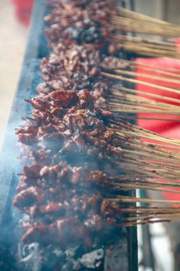 Izgara et şişleri yükselen dumanla birlikte kömürde pişer, yemeye hazırdır. Bu görüntü yemek ve pişirme kavramları için kullanılabilir..