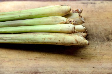 Taze limon otu sapları aşınmış ahşap bir tahtanın üzerinde toplanır ve soluk yeşil renkleri sergilenir. Bu resim Asya mutfağının malzemelerini resmetmek için mükemmeldir..