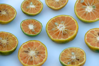 Tohumlu dilimlenmiş turunçgiller, canlı portakal hamurlarını ve yeşil kabuklarını gösteren beyaz bir yüzeye yerleştirilmiştir. Bu meyveyi sağlıklı yemek ve yiyecek kavramı için kullanın..