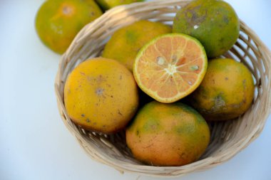 Taze mandalinalar dokuma sepetinde ikiye bölünür. Bu resim yiyeceklerle ilgili projeler ve sağlıklı yaşam tarzı içeriği için mükemmeldir..