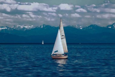 Yalnız bir yelkenli, uzak dağların çerçevelediği yumuşak bir gökyüzünün altında süzülür. Yalnızlık ve zarafeti çağrıştıran minimalist ve şiirsel bir kompozisyon. Tarih: 3 Eylül 2011
