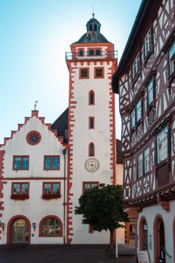 Laufen am Neckar, Almanya 'da tarihi bir saat kulesi, beyaz bir cephe, kırmızı süsleme ve ahşap çerçeveli bir binanın yanında kemerli pencereleri var. Geleneksel Alman mimarisi ve kültürel mirasının güzel bir örneği..