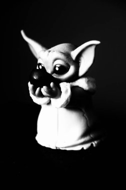 Black-and-white close-up of a whimsical figurine with large ears and eyes, holding a small object. Captured in Germany, this image features dramatic lighting and high contrast, evoking fantasy and character design aesthetics.