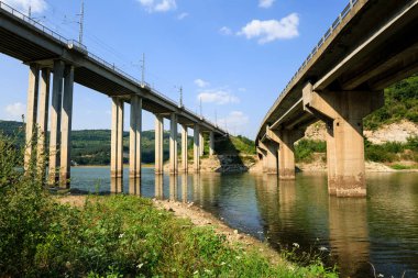 Mavi gökyüzü bulutlu karşı Bulgaristan Luda Kamchia River Tsonevo Barajı üzerinden demiryolu ve otomobil sehpa köprüler. Ulaşım altyapı ayrıntıları