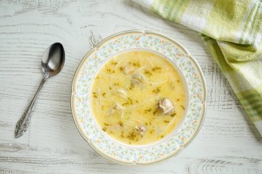 Lezzetli, ev yapımı, geleneksel Bulgar tavuk çorbası (pileshka çorba) yumurta kıvam ile üstten görünüm kaşık ve peçete rustik ahşap tablo