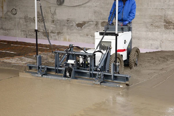 工人用激光熨平板机调配新浇混凝土表面在工地上 — 图库照片