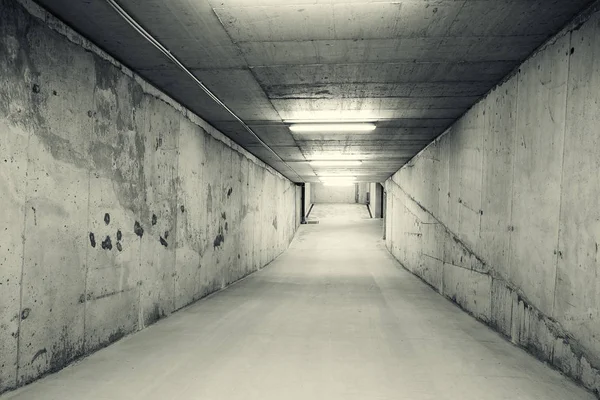 Empty, tunnel like downhill ramp of an underground car parking. Black and white image