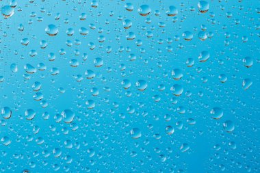 Turkuaz mavi arka plan karşı pencere cam üzerine düşünceler ile makro çekim su damlaları
