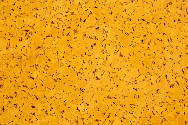 Dark yellow colored rubber floor background texture. Shock absorbent flooring for gyms, playgrounds, sports and running tracks