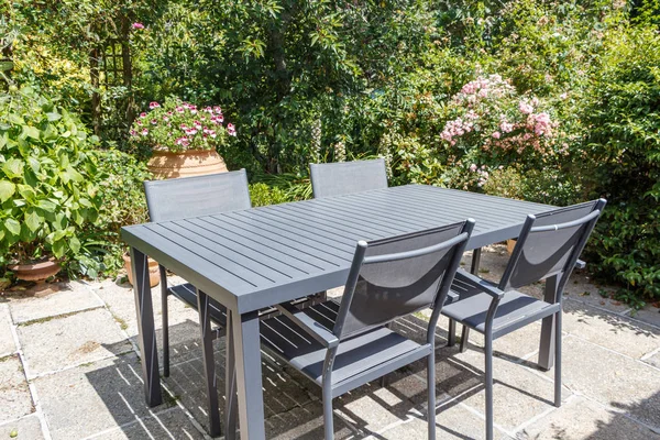 Flowered terrace with grey garden furniture during summer