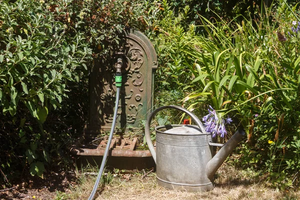 Rega pode, mangueira e fonte em um jardim — Fotografia de Stock