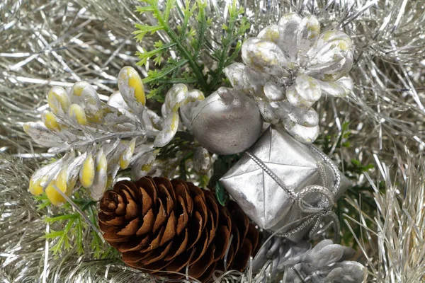 Подарочные и сосновые шишки на серебряной мишуре — стоковое фото
