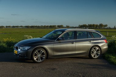 Hollanda - 8 Mayıs, 2017: Hollandalı polder önünde duran bir gün batımı touring Bmw 320i.