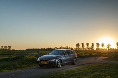 Hollanda - 8 Mayıs, 2017: Hollandalı polder önünde duran bir gün batımı touring Bmw 320i.