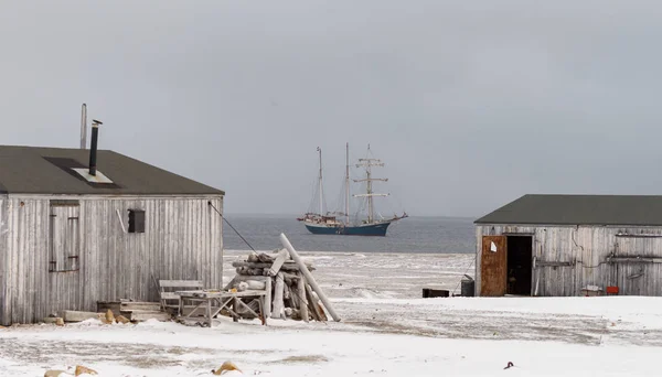 在白雪覆盖的海岸上废弃的木制建筑和在斯匹次卑尔根的海上船只 — 图库照片