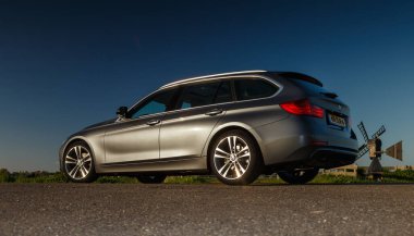 Hollanda 8 Mayıs 2017, bir BMW 320i günbatımında Hollandalı bir polder içinde duruyor..