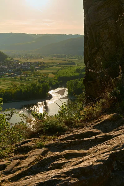 Tuna Nehri 'ne bakan kaya oluşumlarıyla manzaralı dağ manzarası, küçük kasabalar, üzüm bağları ve tepeler Vaçu Vadisi, Avusturya' da altın gün batımı ışığıyla yıkandı..