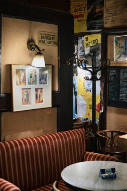 İç köşesinde kırmızı-bej çizgili bir kanepe, küçük bir masa, beş çerçeveli bir lamba ve masanın üzerinde bir rezervasyonlu tabela var..