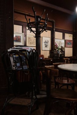Viyana 'da tarihi bir kafe içinde ahşap sandalyeler, ahşap bir askılık bej duvarlar ve pencereden içeri giren bir güneş ışığı var..