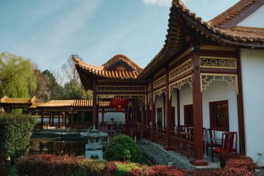 Viyana 'da bir Çin restoranında geleneksel bir avlu var. Temiz çalılar, gölet ve verandada açık hava yemekleri için masalar..