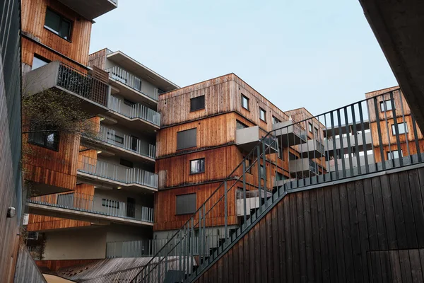 Viyana 'daki modern çok katlı apartman binasında gri bir gökyüzünün altında beton Bauhaus tarzı balkonlar, ahşap kahverengi ön cephe panelleri yer alıyor..