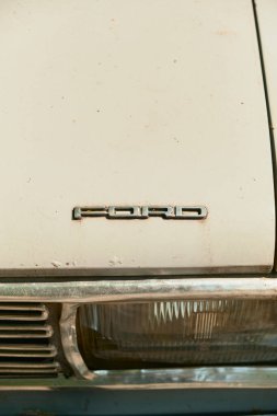 Metalik amblem ve ızgaralı dikdörtgen farlı klasik bir arabanın kaputunun yakın çekimi. Klasik otomobil detayı retro tasarım ve zanaatkarlık sergiliyor.