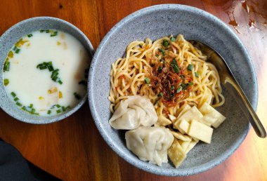 Geleneksel Endonezya tavuklu erişte, mantı, kızarmış wonton ve seramik kaselerde ayrı çorba çorbası ile servis edilir..