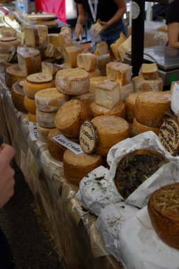 Large display of artisanal cheese wheels and wedges at outdoor market stall during Cheese 2025, the biennial Slow Food festival in Bra, Italy. Various aged cheeses including pecorino and local varieties are displayed with price labels.