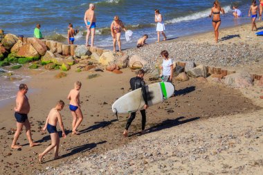 Zelenogradsk, Kaliningrad bölgesi, Rusya Federasyonu - 29 Temmuz 2017: Bilinmeyen sörfçü ünlü tatil Zelenogradsk yaz saati, Baltık Denizi kıyılarının sahilde surfboard ile.