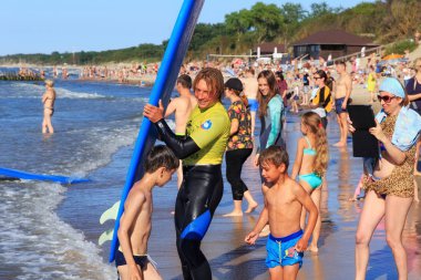 Zelenogradsk, Kaliningrad bölgesi, Rusya Federasyonu - 29 Temmuz 2017: Bilinmeyen sörfçü ile ünlü tatil Zelenogradsk yaz saati, Baltık Denizi kıyısında kumlu bir plaj üzerinde sörf tahtası duran.
