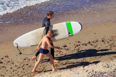 Zelenogradsk, Kaliningrad bölgesi, Rusya Federasyonu - 29 Temmuz 2017: Bilinmeyen sörfçü ünlü tatil Zelenogradsk yaz saati, Baltık Denizi kıyılarının sahilde surfboard ile.