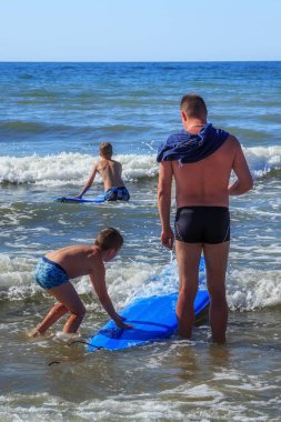 Zelenogradsk, Kaliningrad bölgesi, Rusya Federasyonu - 29 Temmuz 2017: Bilinmeyen çocuk dinlenme ve yaz saati, Baltık Denizi'nin mavi dalgalar üzerinde sörf öğrenme surfboard ile.
