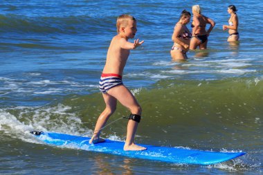 Zelenogradsk, Kaliningrad bölgesi, Rusya Federasyonu - 29 Temmuz 2017: Bilinmeyen çocuk dinlenme ve yaz saati, Baltık Denizi'nin mavi dalgalar üzerinde sörf öğrenme sörf tahtası üzerinde.