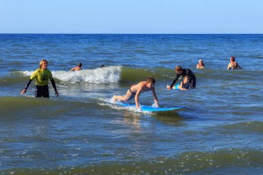 Zelenogradsk, Kaliningrad bölgesi, Rusya Federasyonu - 29 Temmuz 2017: dinlenme ve yaz saati, Baltık Denizi'nin mavi dalgalar üzerinde profesyonel eğitmenler ile sörf öğrenme bilinmeyen çocuk.