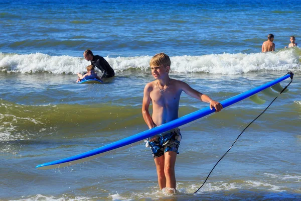 Zelenogradsk, Kaliningrad bölgesi, Rusya Federasyonu - 29 Temmuz 2017: Bilinmeyen çocuk dinlenme ve yaz saati, Baltık Denizi'nin mavi dalgalar üzerinde sörf öğrenme surfboard ile.