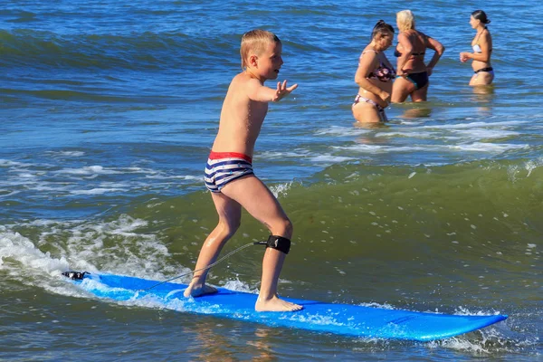 Zelenogradsk, Kaliningrad bölgesi, Rusya Federasyonu - 29 Temmuz 2017: Bilinmeyen çocuk dinlenme ve yaz saati, Baltık Denizi'nin mavi dalgalar üzerinde sörf öğrenme sörf tahtası üzerinde.