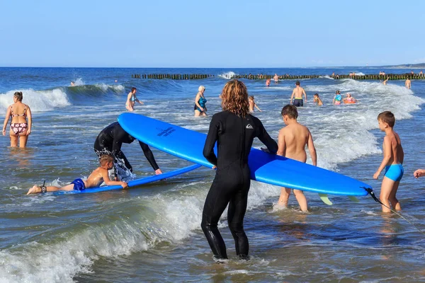 Zelenogradsk, Kaliningrad bölgesi, Rusya Federasyonu - 29 Temmuz 2017: Bilinmeyen surfer sörf tahtası ayakta bilinmeyen çocuk yakınındaki ile kim yaz saati Baltık denizde dalgalar sörf öğrenme.