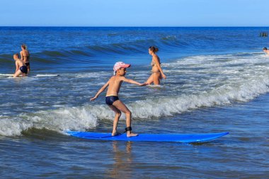 Zelenogradsk, Kaliningrad bölgesi, Rusya Federasyonu - 29 Temmuz 2017: Bilinmeyen çocuk dinlenme ve yaz saati, Baltık Denizi'nin mavi dalgalar üzerinde sörf öğrenme sörf tahtası üzerinde.