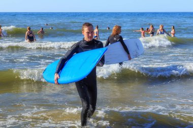 Zelenogradsk, Kaliningrad bölgesi, Rusya Federasyonu - 29 Temmuz 2017: Bilinmeyen sörfçü Baltık Denizi'nin mavi sularına yaz zaman ayakta sörf tahtaları ile.