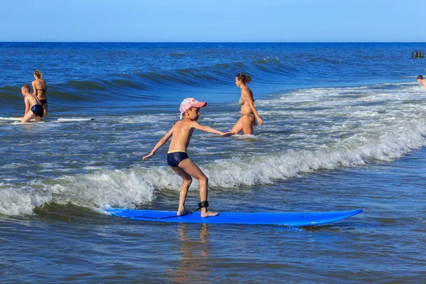 Zelenogradsk, Kaliningrad bölgesi, Rusya Federasyonu - 29 Temmuz 2017: Bilinmeyen çocuk dinlenme ve yaz saati, Baltık Denizi'nin mavi dalgalar üzerinde sörf öğrenme sörf tahtası üzerinde.