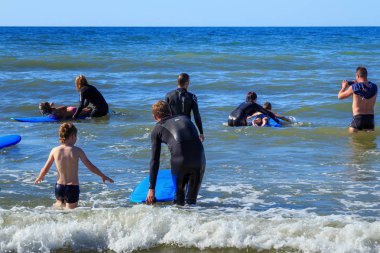 Zelenogradsk, Kaliningrad bölgesi, Rusya Federasyonu - 29 Temmuz 2017: dinlenme ve yaz saati, Baltık Denizi'nin mavi dalgalar üzerinde profesyonel eğitmenler ile sörf öğrenme bilinmeyen çocuk.