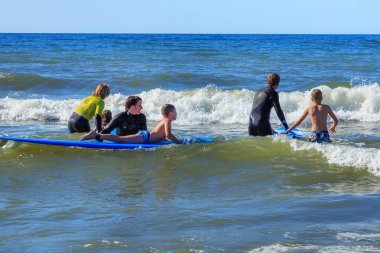 Zelenogradsk, Kaliningrad bölgesi, Rusya Federasyonu - 29 Temmuz 2017: dinlenme ve yaz saati, Baltık Denizi'nin mavi dalgalar üzerinde profesyonel eğitmenler ile sörf öğrenme bilinmeyen çocuk.