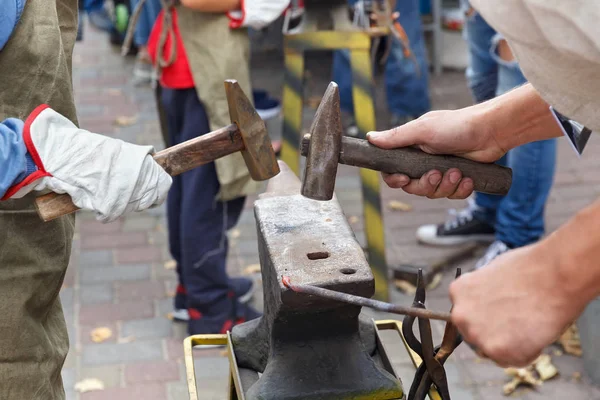 Work with hammers on the anvil in the street forge workshop.