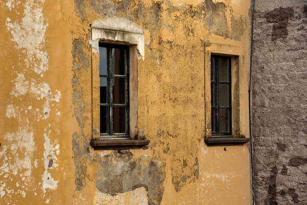Old shabby wall of building with wooden windows.